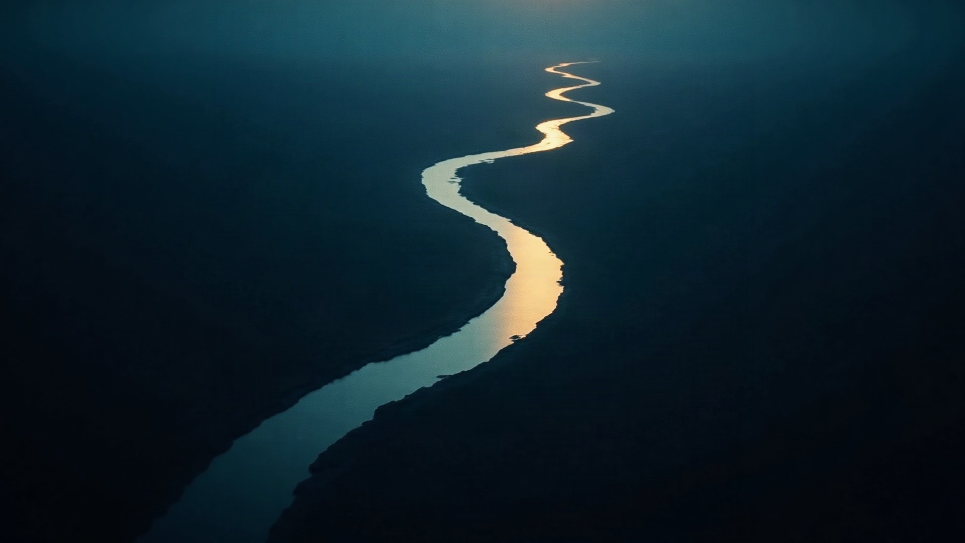 Vue aérienne nocturne d'une rivière dorée serpentant dans un paysage sombre