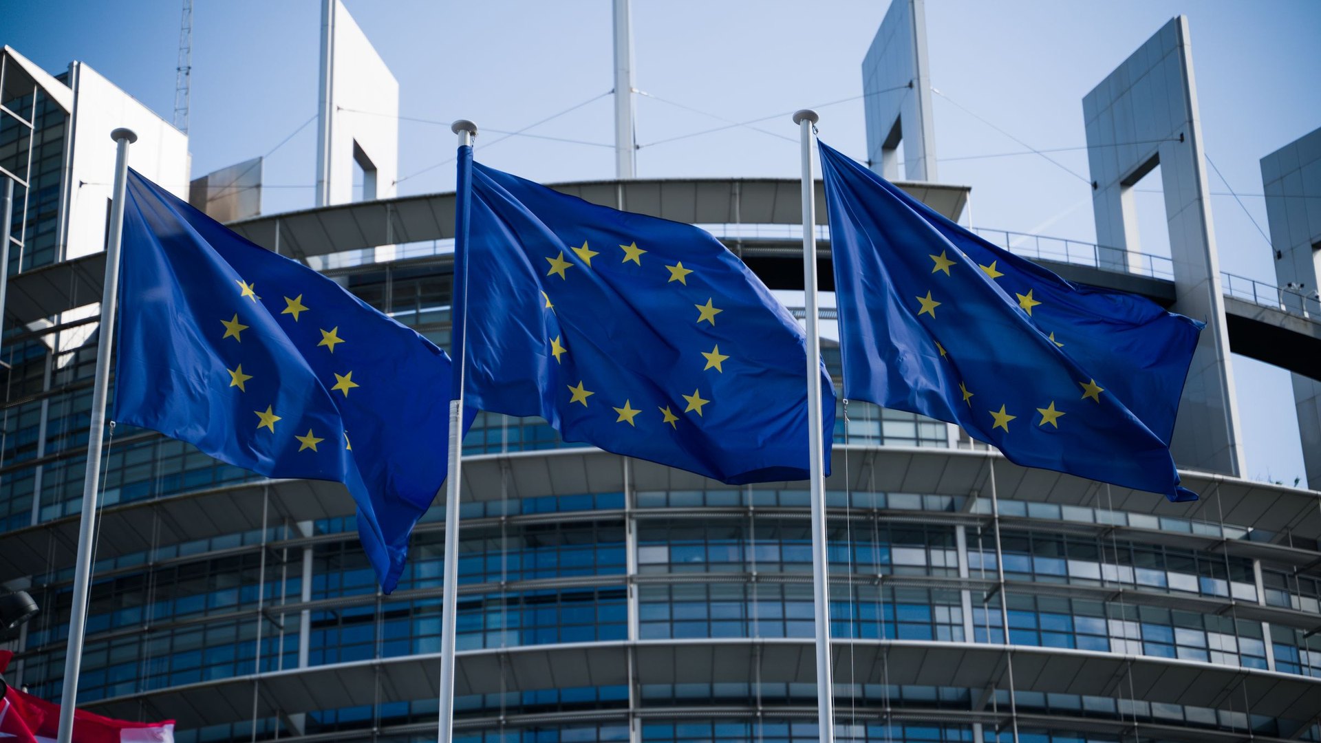 Drapeaux de l'Union européenne flottant devant un bâtiment institutionnel en verre